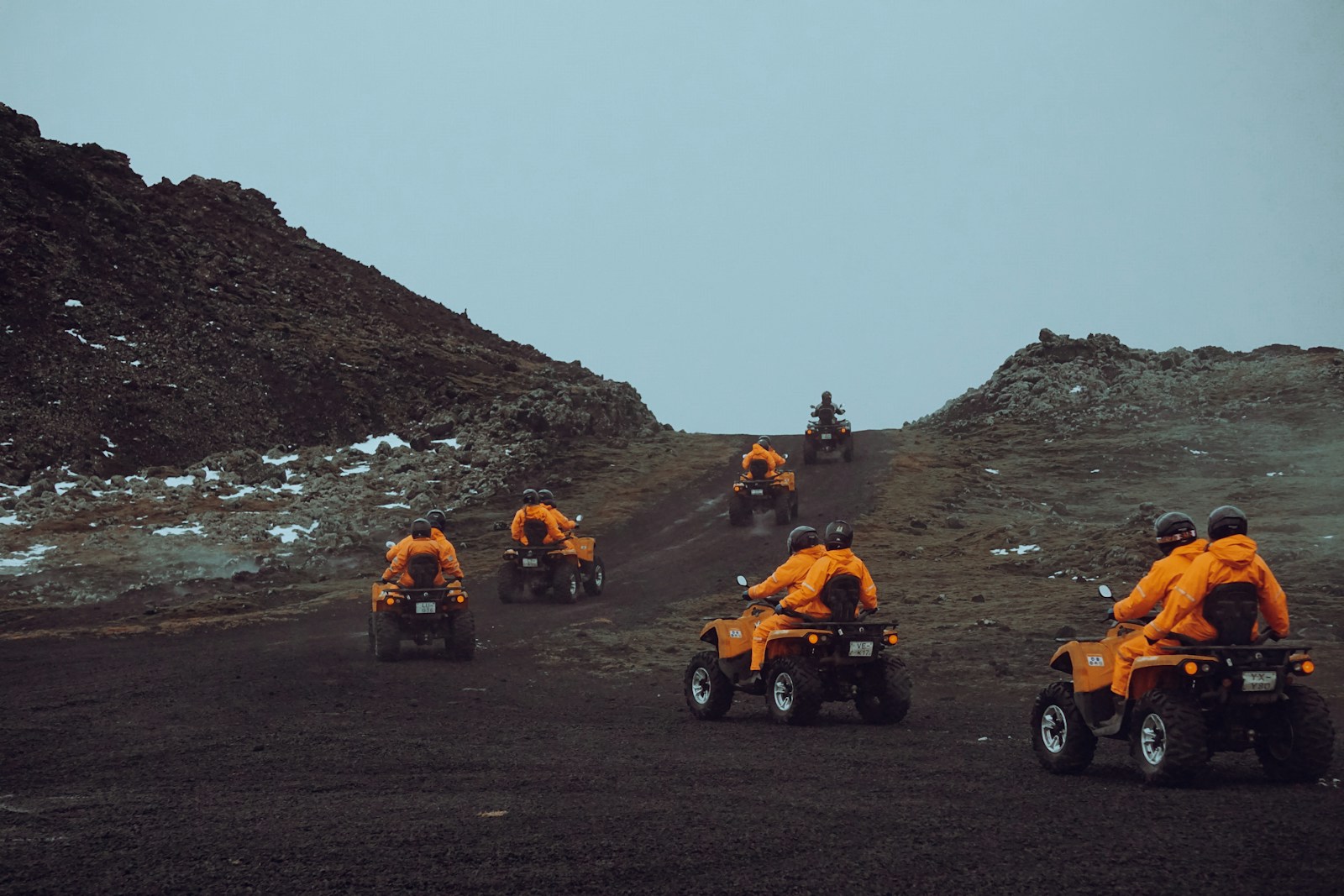 a group of people riding four wheelers down a hill
